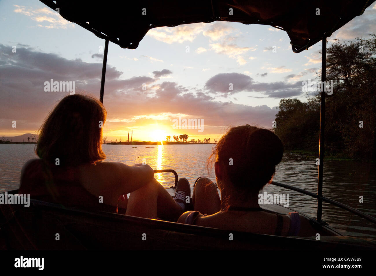 Zwei Frauen, die einen afrikanischen Sonnenuntergang über See Manze in einem Boot, reserve Selous Game, Tansania Afrika Stockfoto