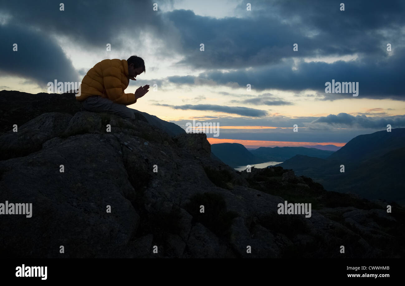 Ein Mann auf dem Gipfel eines Berges zu Gott zu beten. Stockfoto