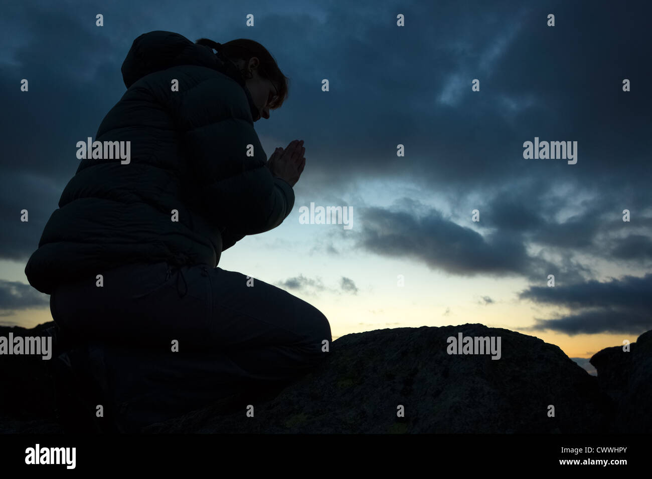 Eine Frau auf dem Gipfel eines Berges zu Gott zu beten. Stockfoto