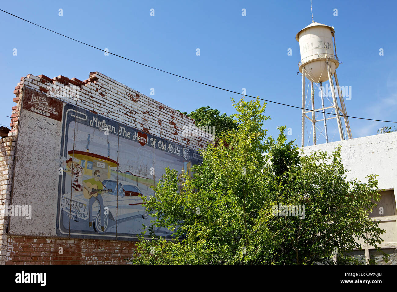 Wandbild auf einer bröckelnden Mauer mit einem Wasserturm im Hintergrund entlang der Route 66 in McLean, Texas verblasst Stockfoto
