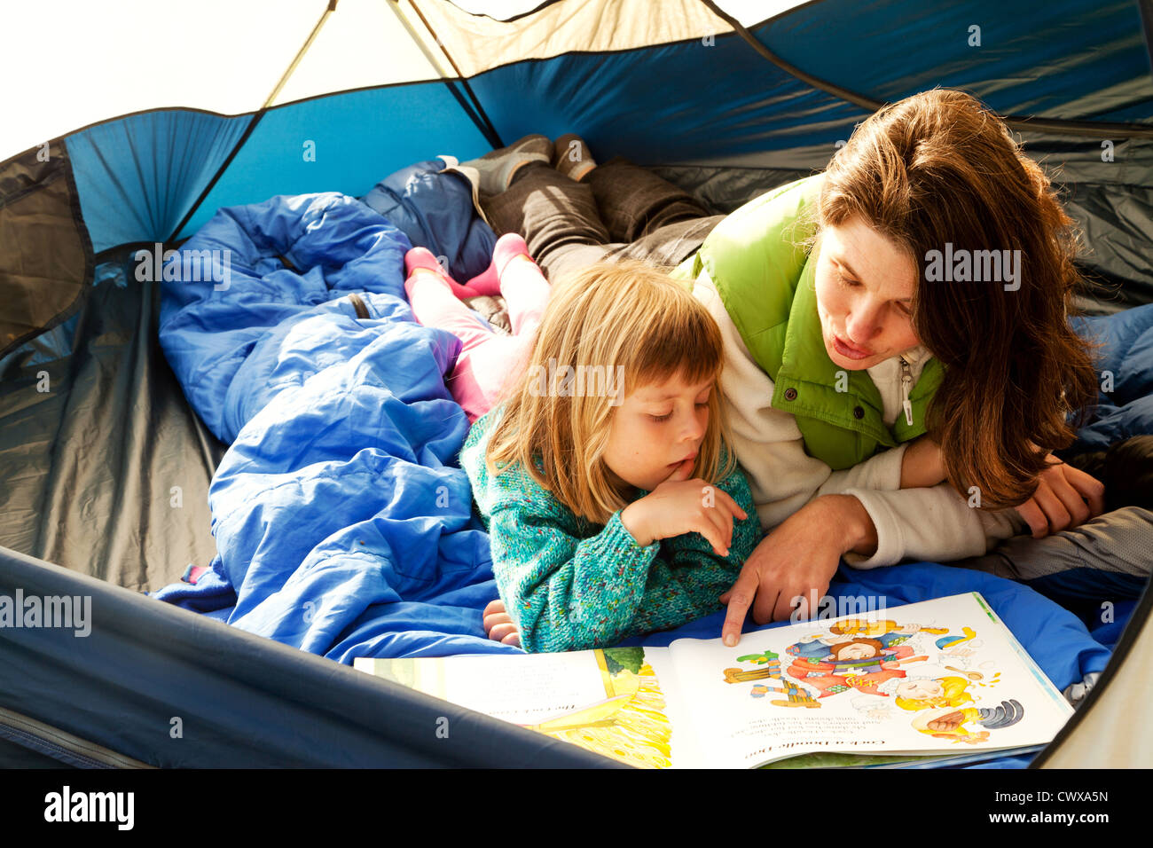 Mutter und Tochter liegen in einem Zelt lesen. Stockfoto