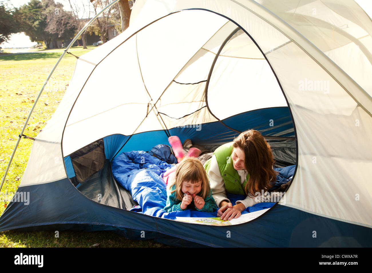 Mutter und Tochter liegen in einem Zelt lesen. Stockfoto
