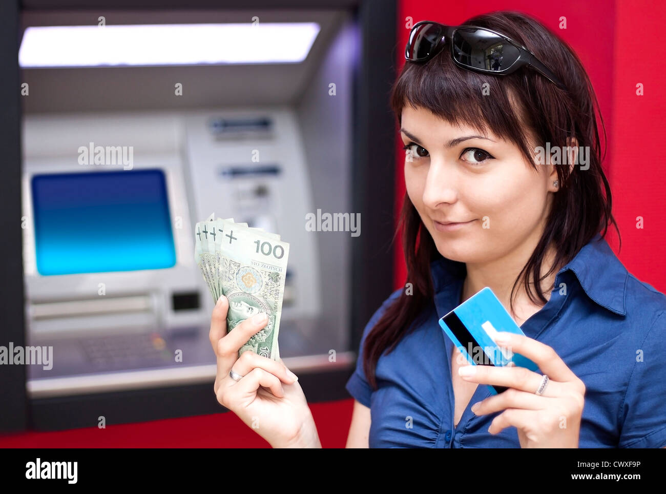 Schöne Frau mit Kreditkarte, sie ist zieht Geld von einem Geldautomaten. Stockfoto