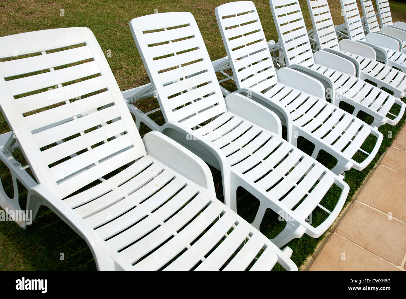 Eine Reihe von weißen Sonnenliege Stühlen von einem Schwimmbad in der Dordogne, Aquitaine, Frankreich Stockfoto