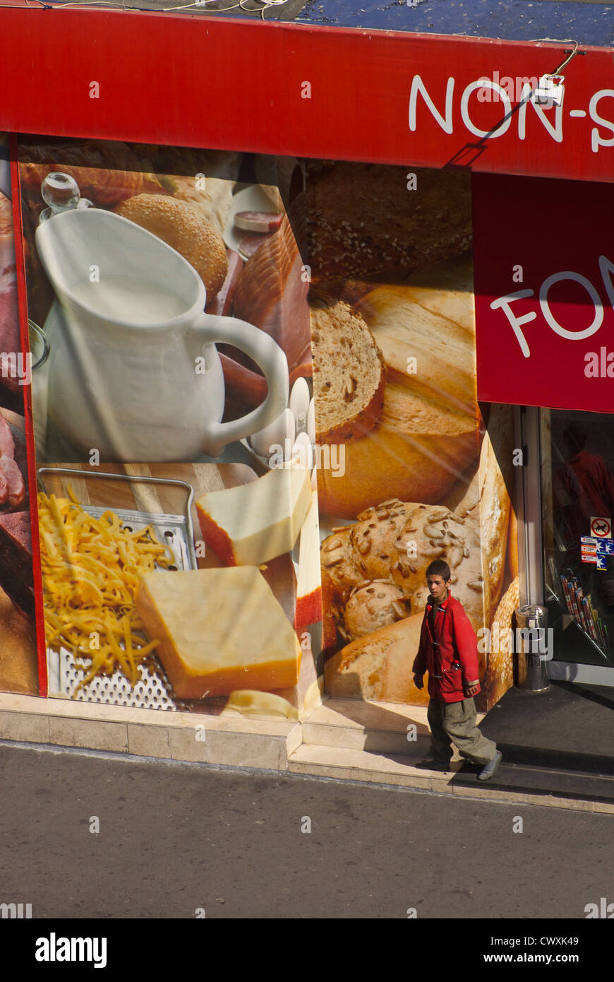 Shoeless Rumänisch Straße Kind verspottet von Diplays an köstlichen Speisen nach Prüfung der Behälter in einem Nonstop-Supermarkt. Stockfoto