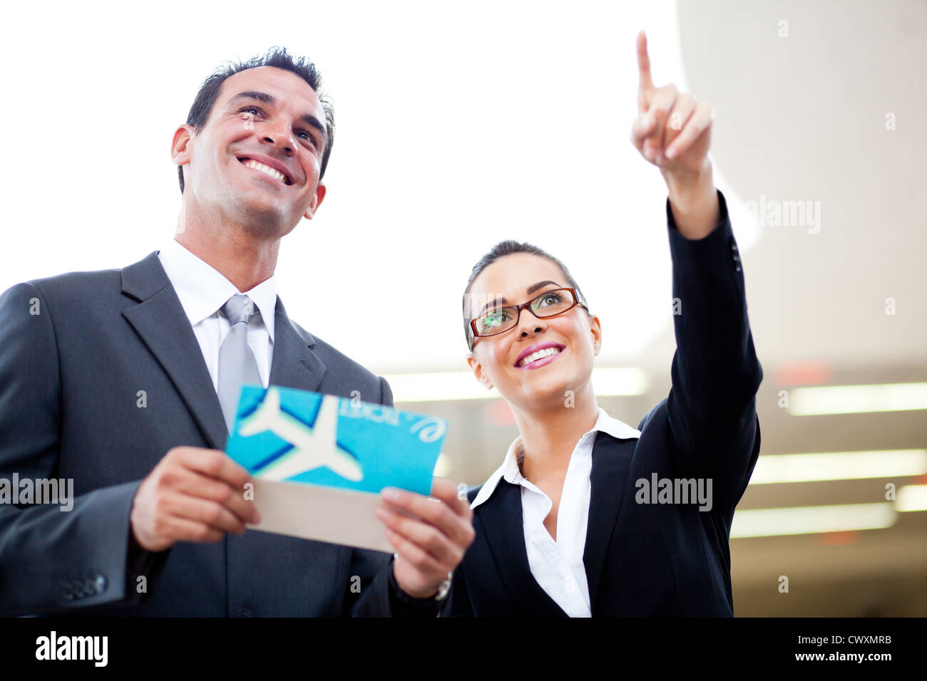 junge Unternehmer und Unternehmerin Blick auf boarding Informationen am Flughafen Stockfoto