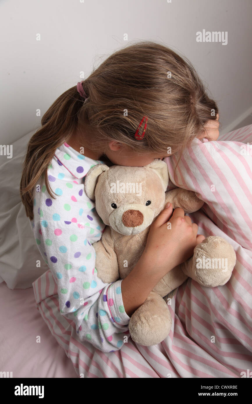 Junges Mädchen im Bett kuscheln einen Teddybär. Stockfoto