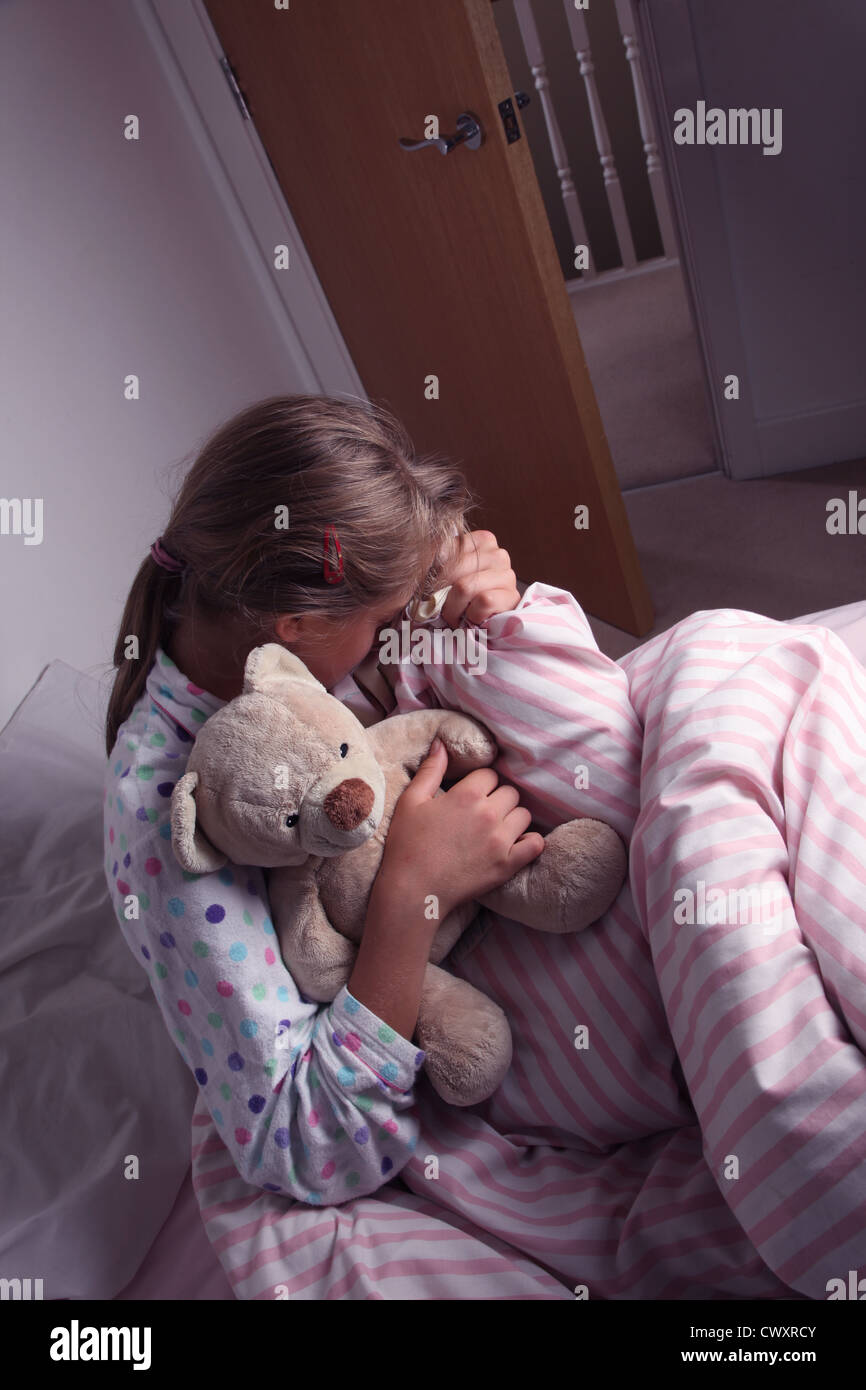 Junges Mädchen im Bett kuscheln einen Teddybär. Stockfoto