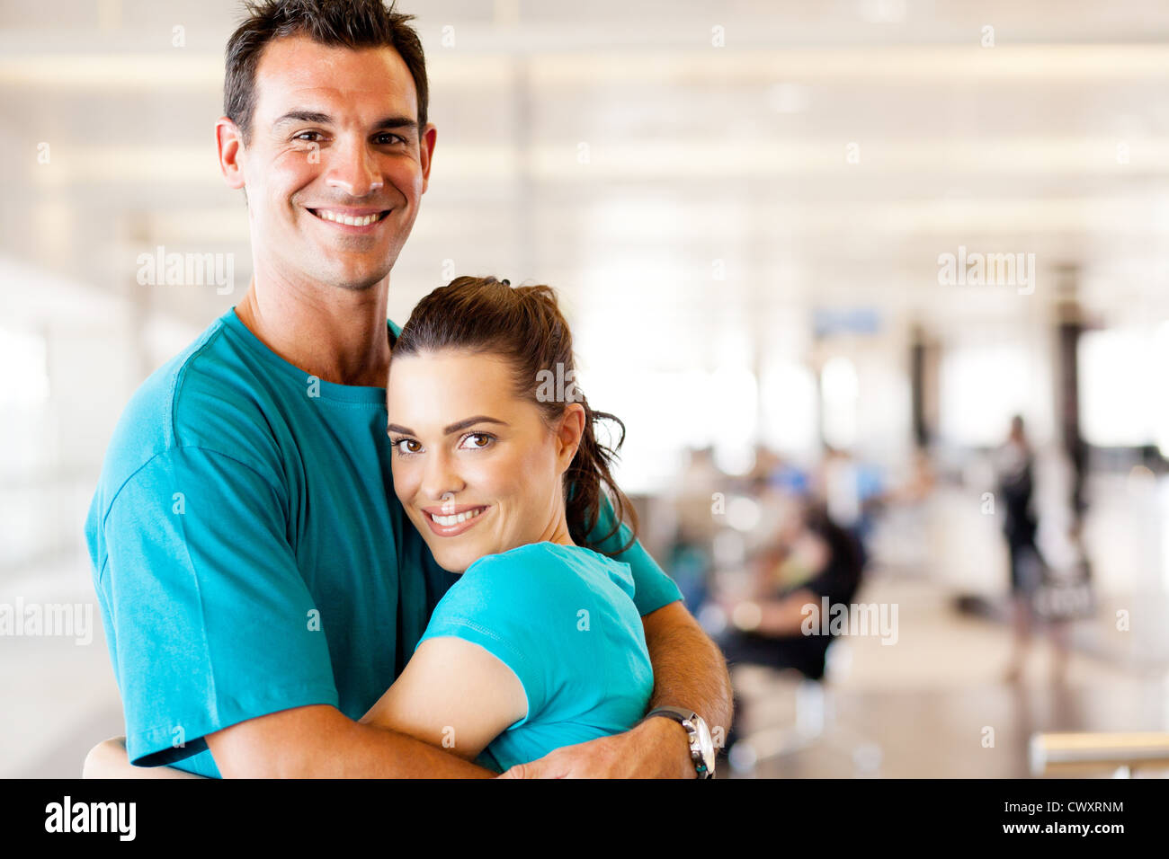 glückliches junges Paar umarmt am Flughafen Stockfoto