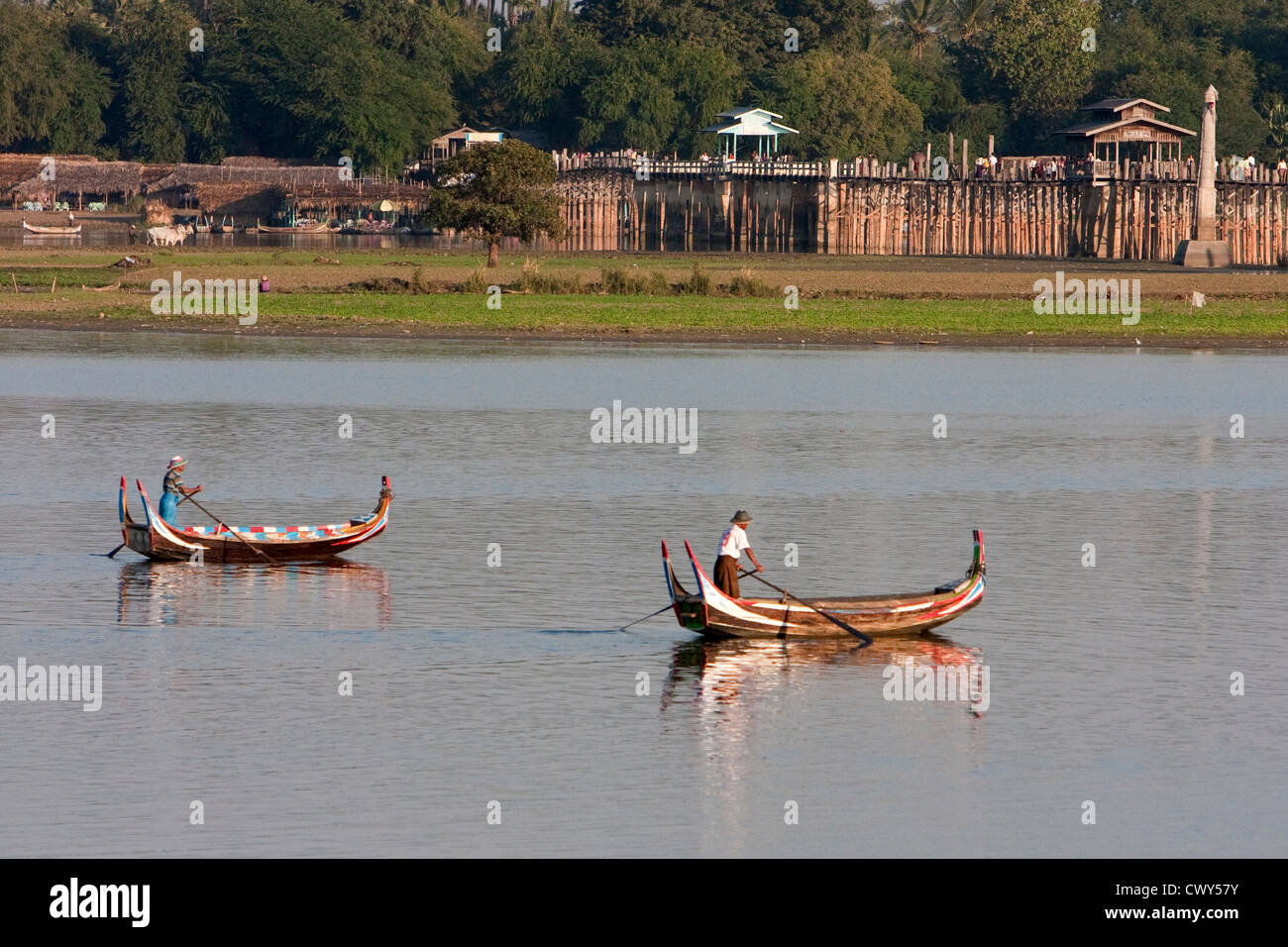 Myanmar, Burma, Mandalay. Taungthaman-See. Zwei Boote am Nachmittag Sonne, U Bein Brücke im Hintergrund. Stockfoto