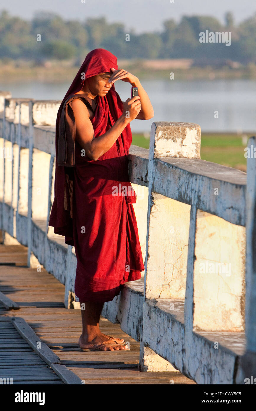 Myanmar, Burma, Mandalay. Buddhistischer Mönch Handy-Aufnahme auf die U Bein Brücke, Amarapura. Stockfoto