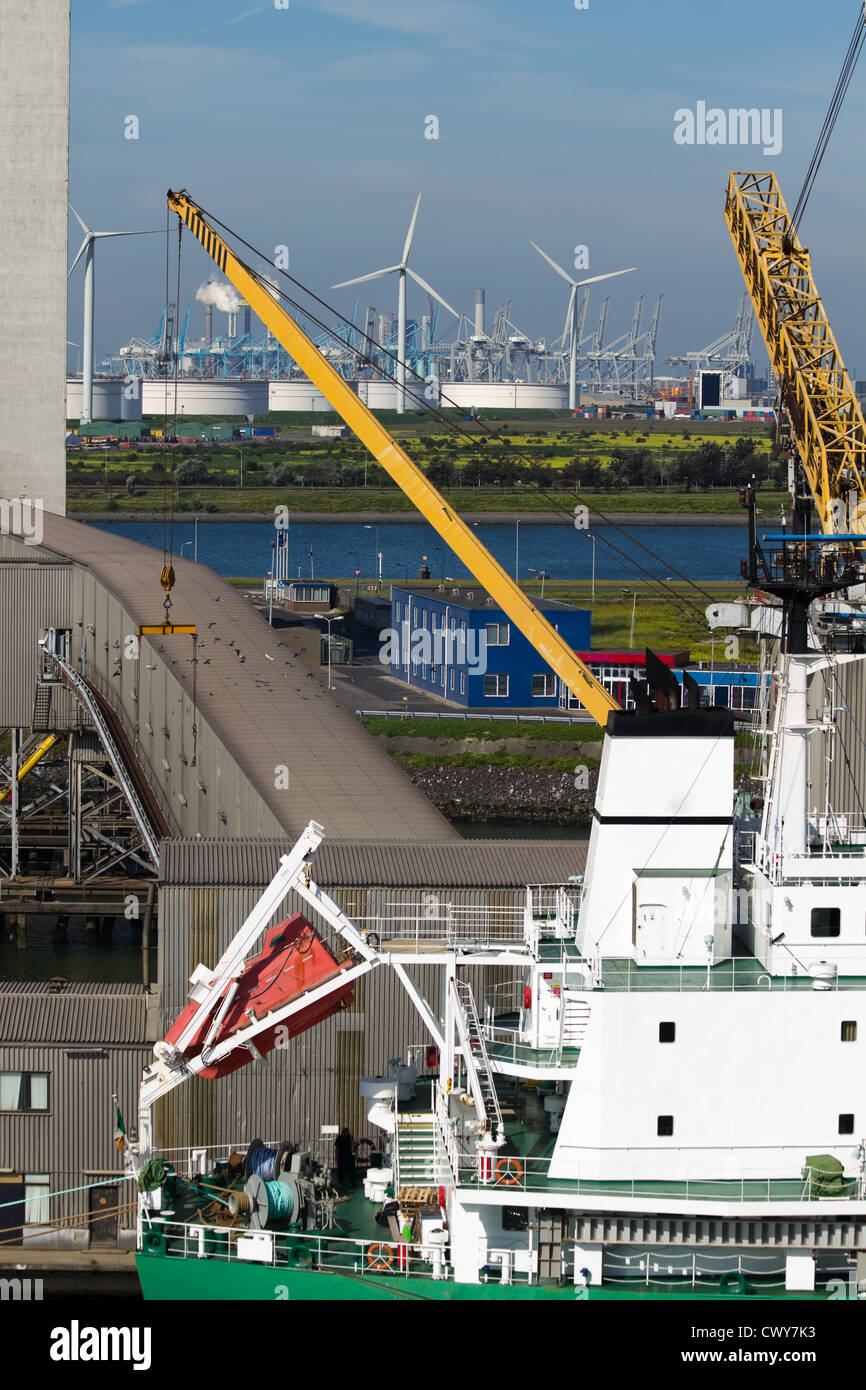 Nahaufnahme des Schiffes am Terminal mit Industriebauten und Windmühlen im Hintergrund Stockfoto