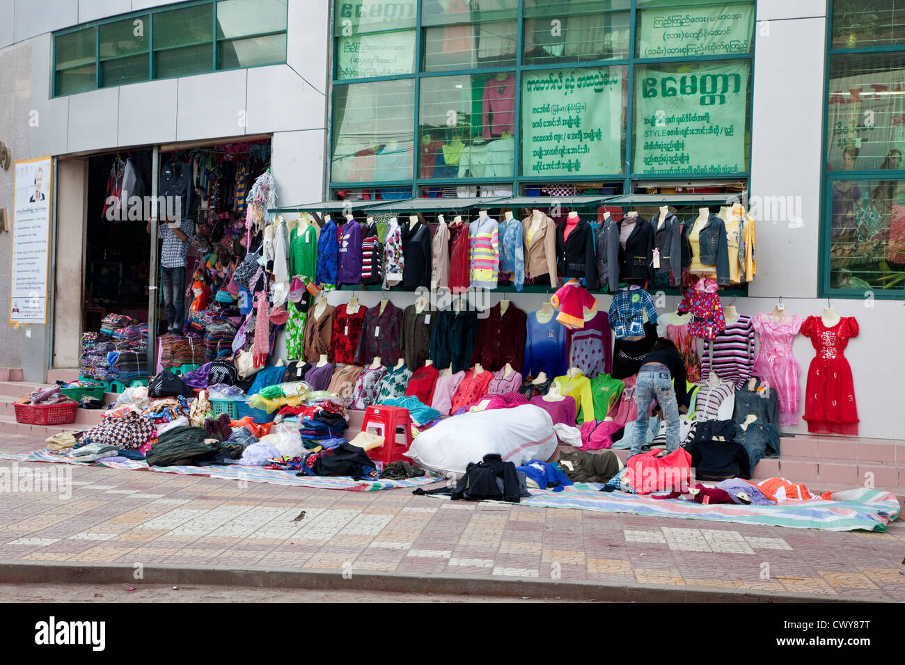 Myanmar, Burma. Mandalay. Kleidung Shop Ware Spill aus dem Laden auf dem Bürgersteig in Downtown Mandalay. Stockfoto