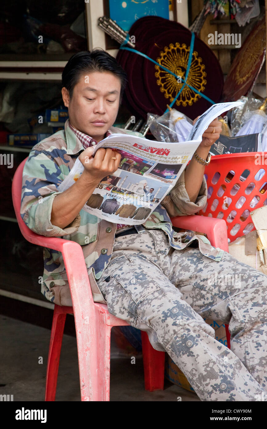 Myanmar, Burma. Mandalay. Burmesische Mann lesen Zeitung. Stockfoto