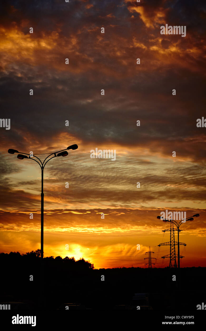 Powerlines und eine Straße-Laterne bei Sonnenuntergang. Vertikale erschossen Stockfoto