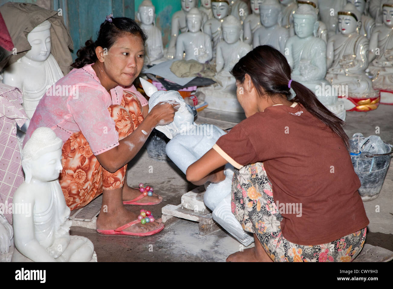 Myanmar, Burma, Mandalay. Frauen-Handwerkern bei der Arbeit Polieren Buddha aus Stein gehauen. Viele werden nach China exportiert. Stockfoto