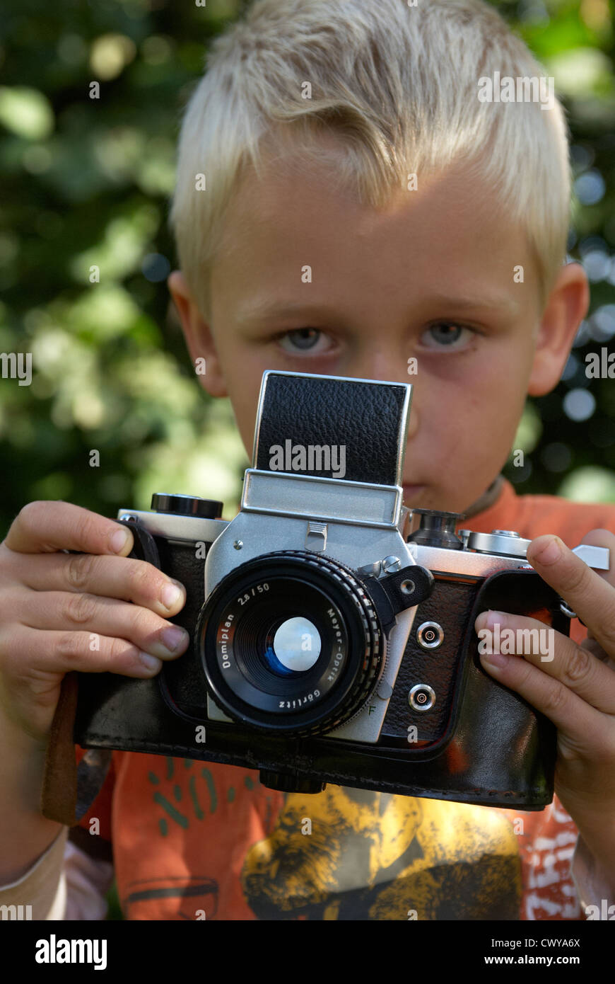 Kind blonde junge halten und Fotografieren mit Vintage-Kamera draußen Sommer Stockfoto