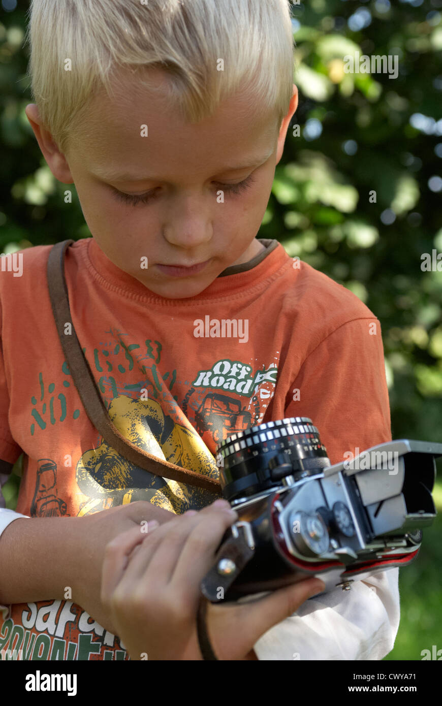 Kind blonde junge halten und Fotografieren mit Vintage-Kamera draußen Sommer Stockfoto