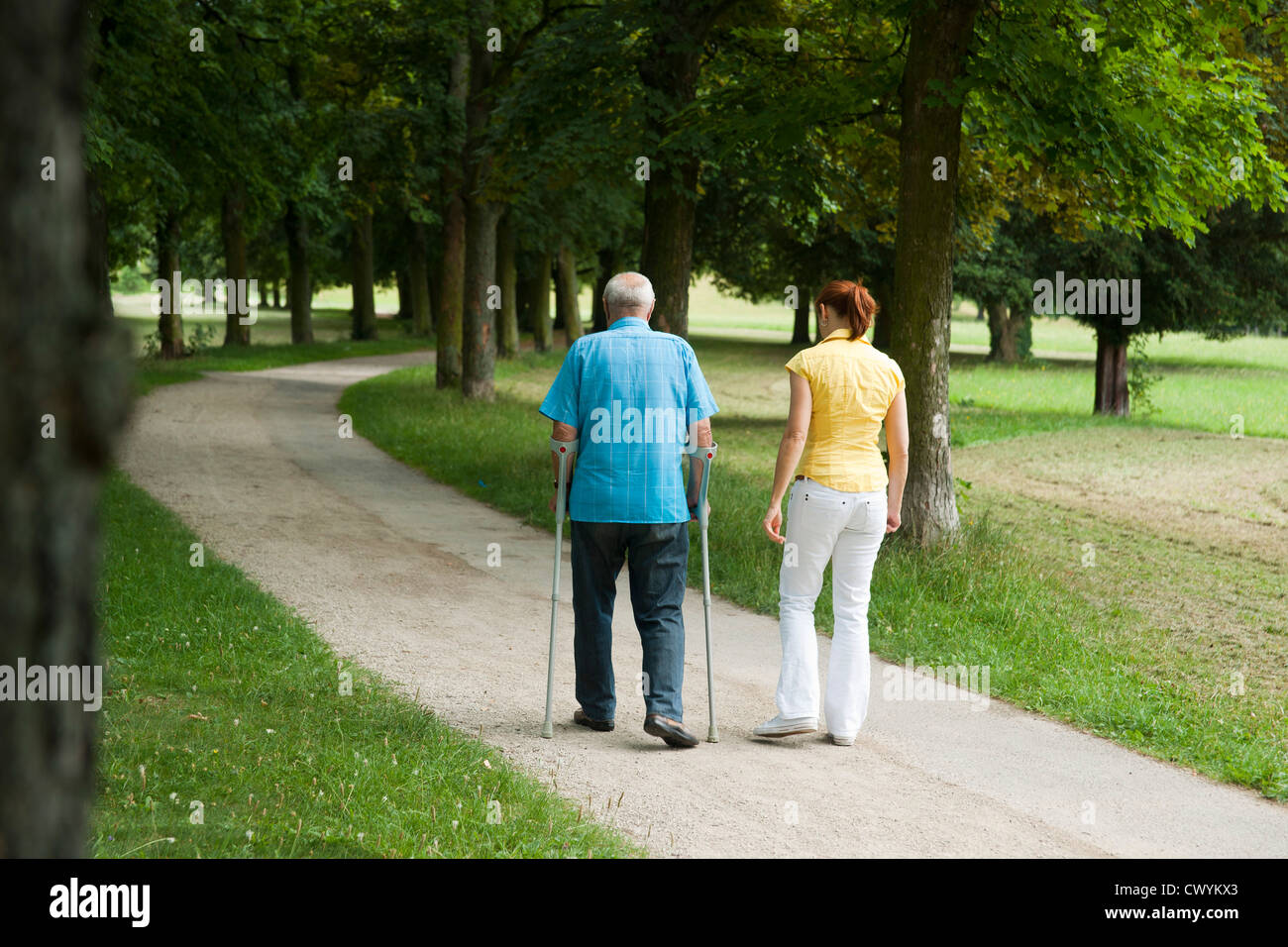 Frau zu Fuß mit alten Mann im park Stockfoto