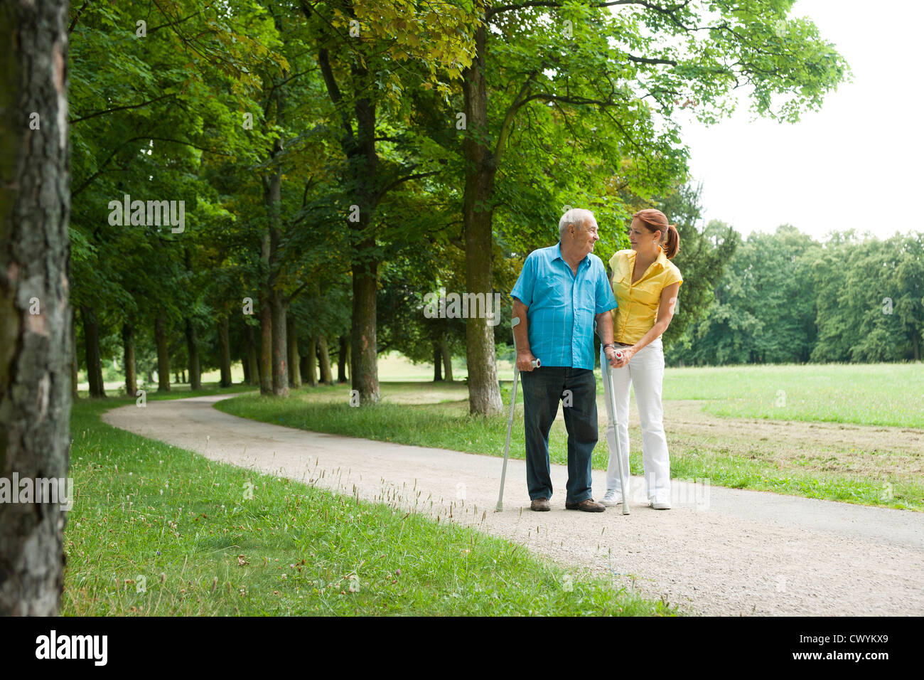 Frau zu Fuß mit alten Mann im park Stockfoto