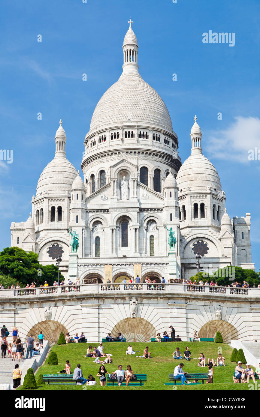 Menschenmengen saßen auf dem Rasen unter Sacre Coeur im Quadrat Louise Michel Paris Frankreich Europa EU Stockfoto