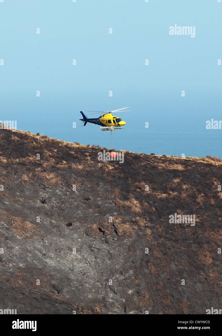 Feuer Hubschrauber fliegen über ausgebrannte Landschaft nach Waldbrände an der Costa Del Sol Stockfoto