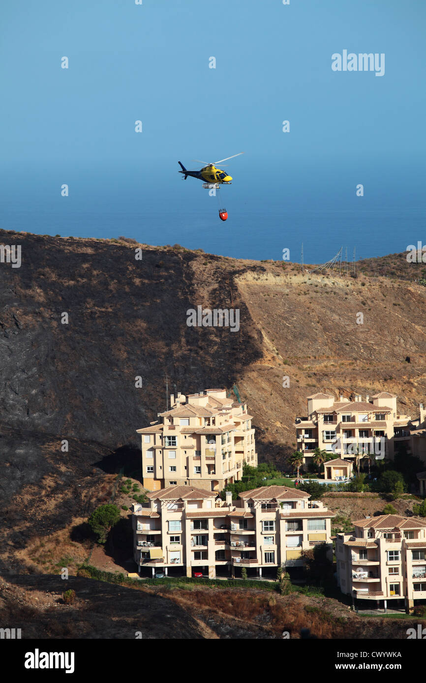 Feuer Hubschrauber fliegen über Wohnungen nach Waldbrände an der Costa Del Sol Stockfoto