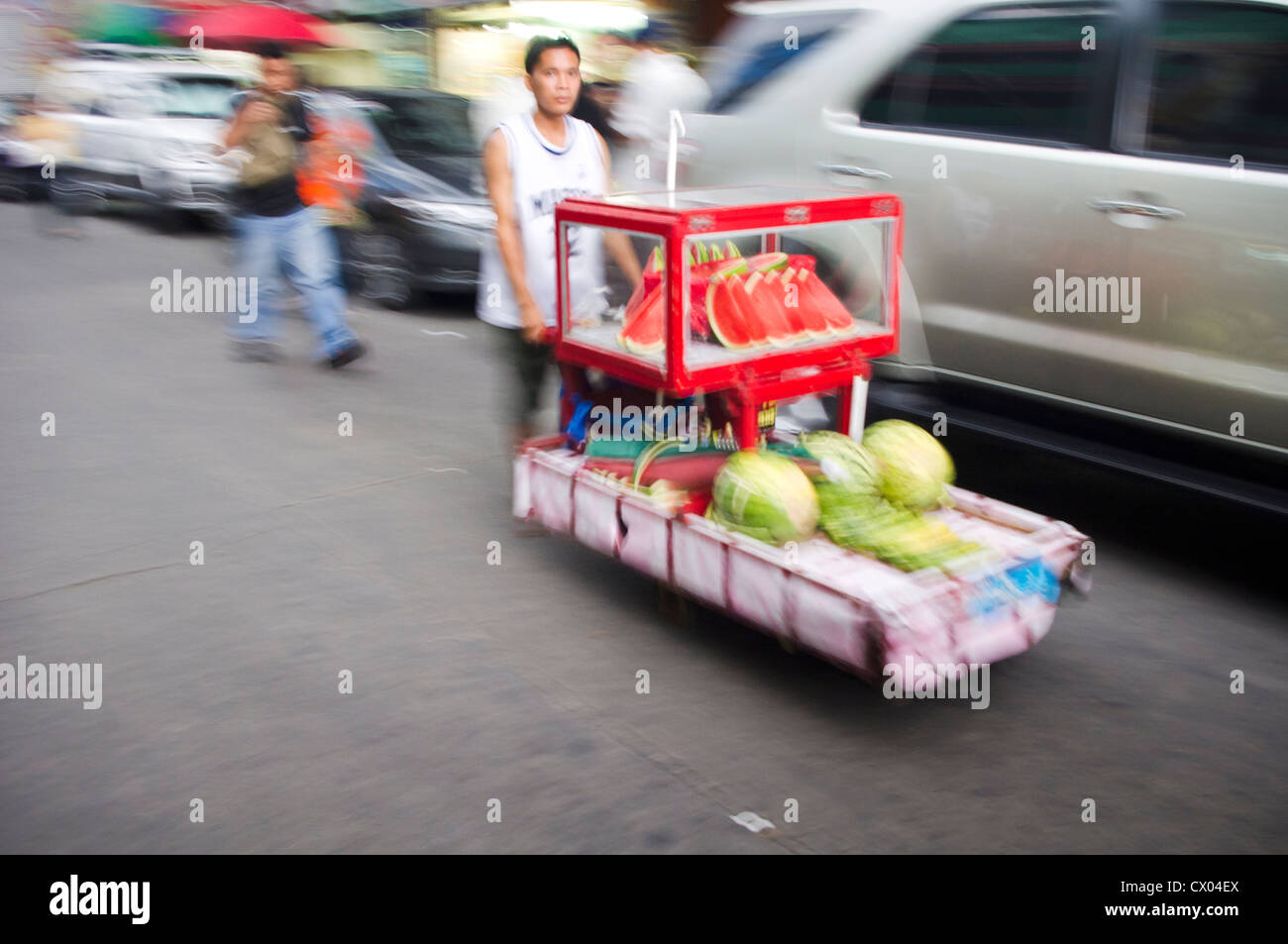 Ein Obsthändler drängt seinen Karren. Stockfoto