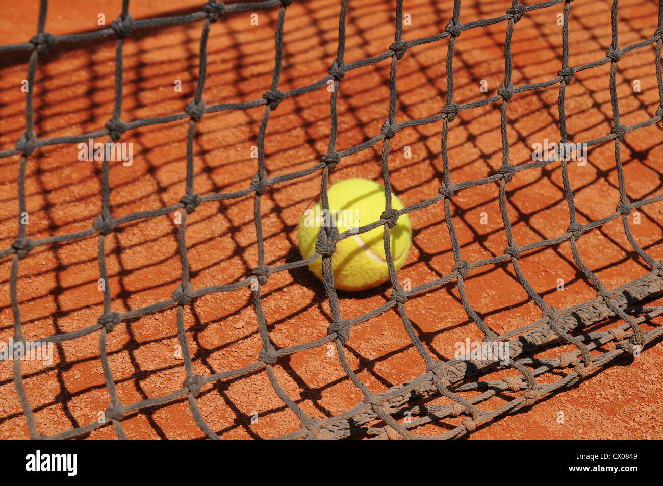 Tennisball auf Platz hinter Net. Stockfoto