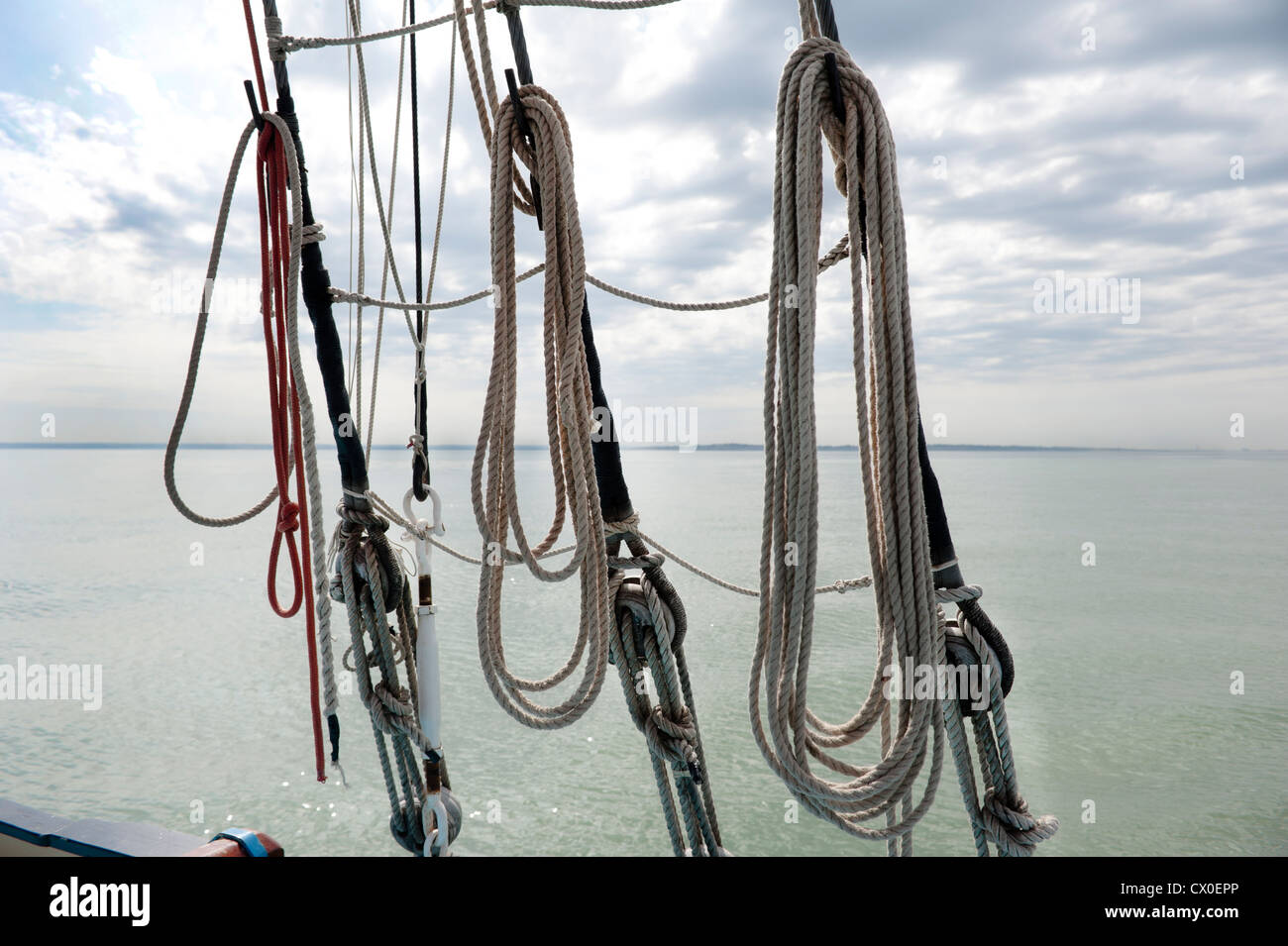 Bestandteil einer Schiffe rigging und hängenden gewickelte Seil an Bord eines Segelschiffes mit Wasser entfernten Küste Stockfoto