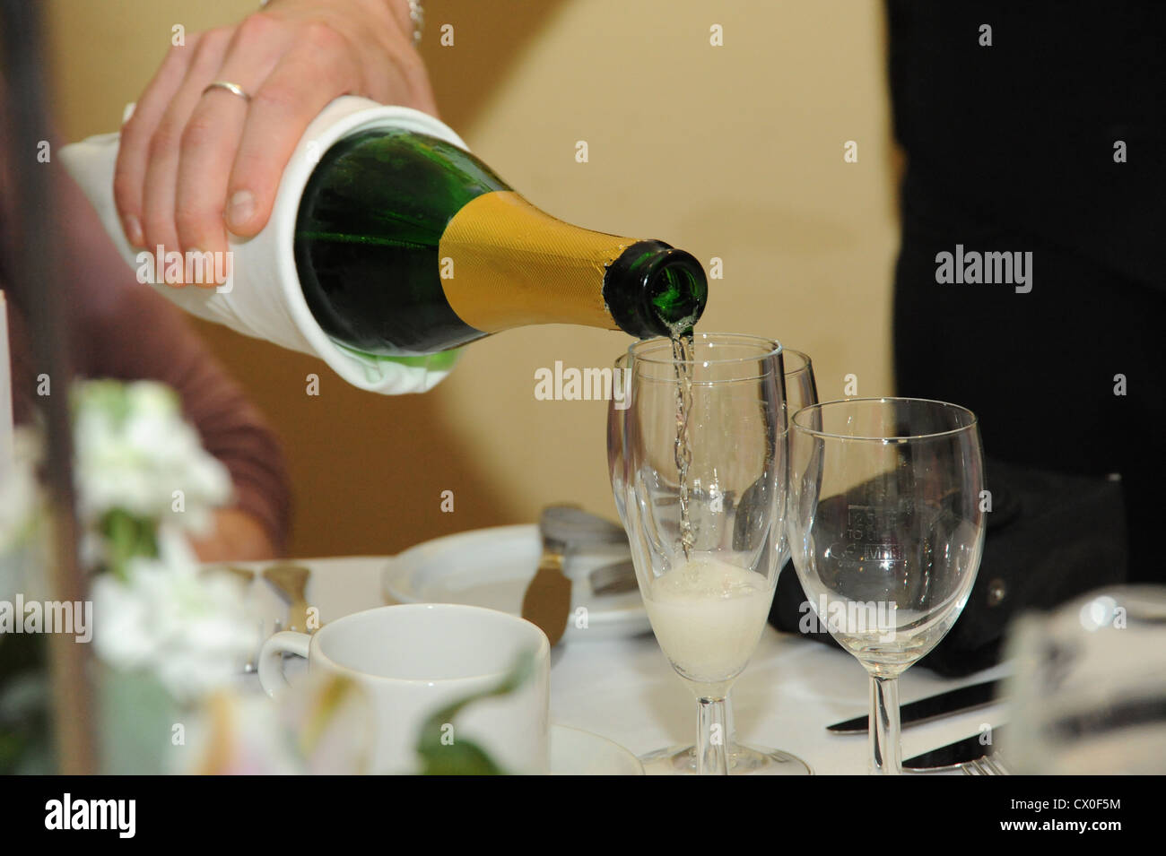 Gießen Champagner in Champagner-Flöten Stockfoto