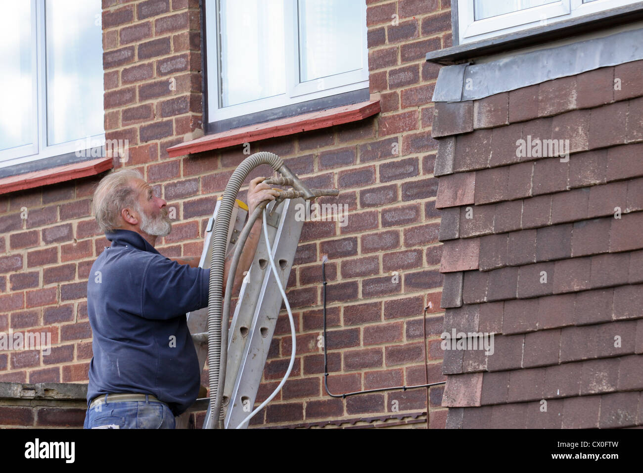 Arbeiter Pumpen Polystyrol Bead Raumwandisolierung in Vorstadthaus in Großbritannien Stockfoto