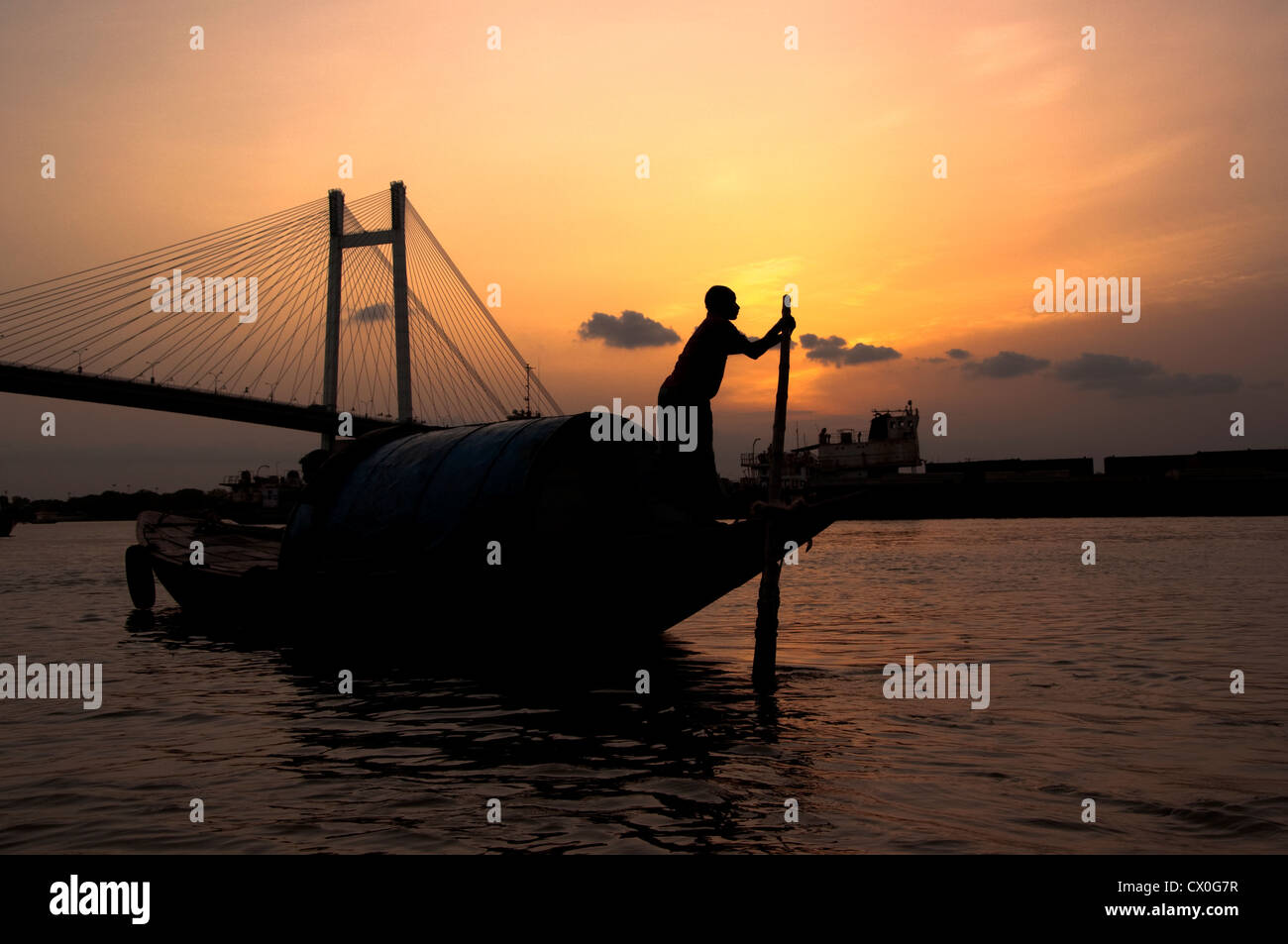 Ein Bootsmann segelt abends sein Boot über den Ganges in Kalkutta, Indien. Stockfoto
