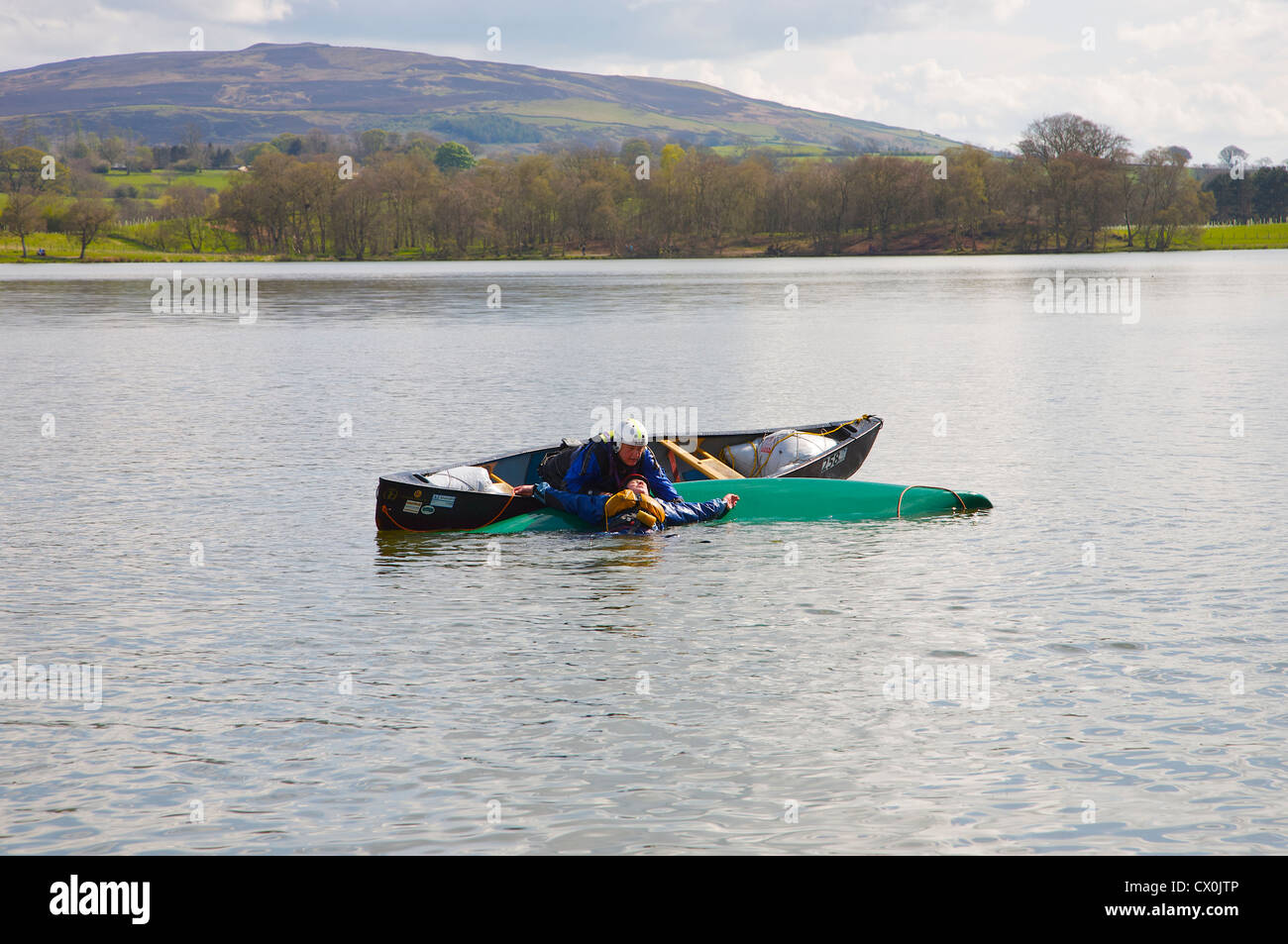 Kanu Rettung Praxis Mann Unfall in kanadisches Kanu zu heben. Talkin Tarn in der Nähe von Brampton, Cumbria, England Stockfoto