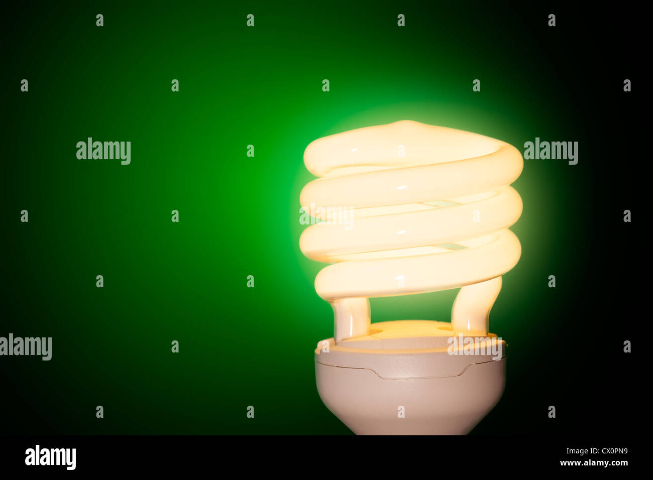 Energiesparende Glühbirne auf grünem Hintergrund. Stockfoto