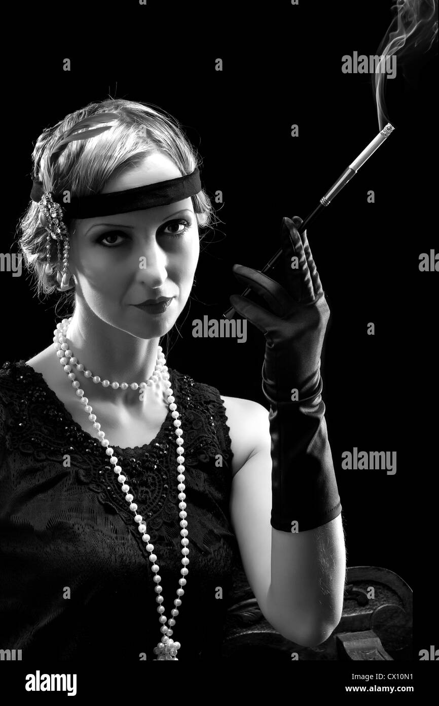 Frau in Flapper Kleid im 20er Jahre Stil, eine Zigarette rauchend  Stockfotografie - Alamy