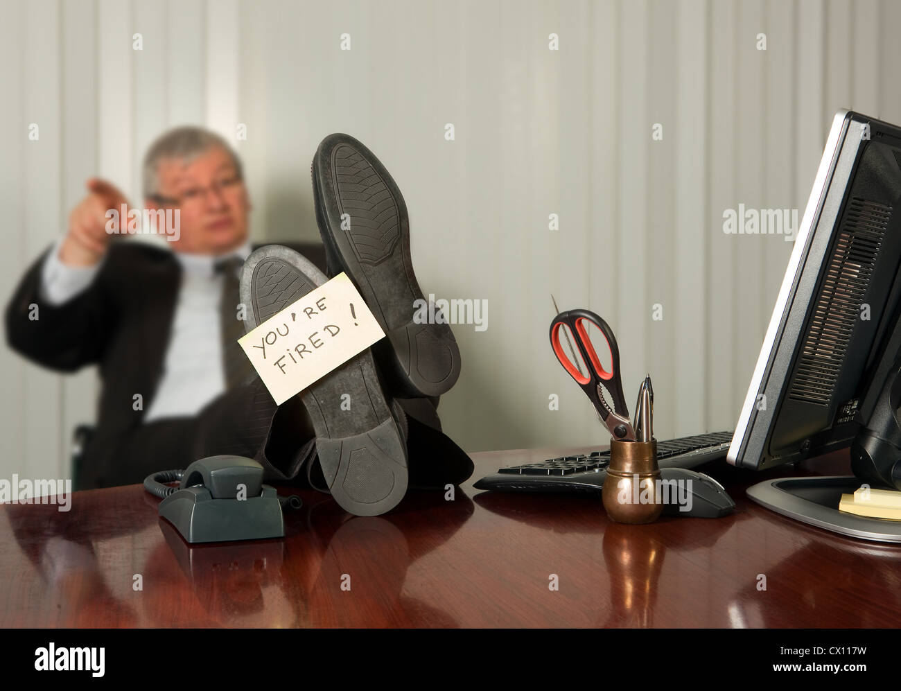 Office Manager feuern eines Mitarbeiters mit einem gelben klebrigen Hinweis auf seinen Schuh Stockfoto