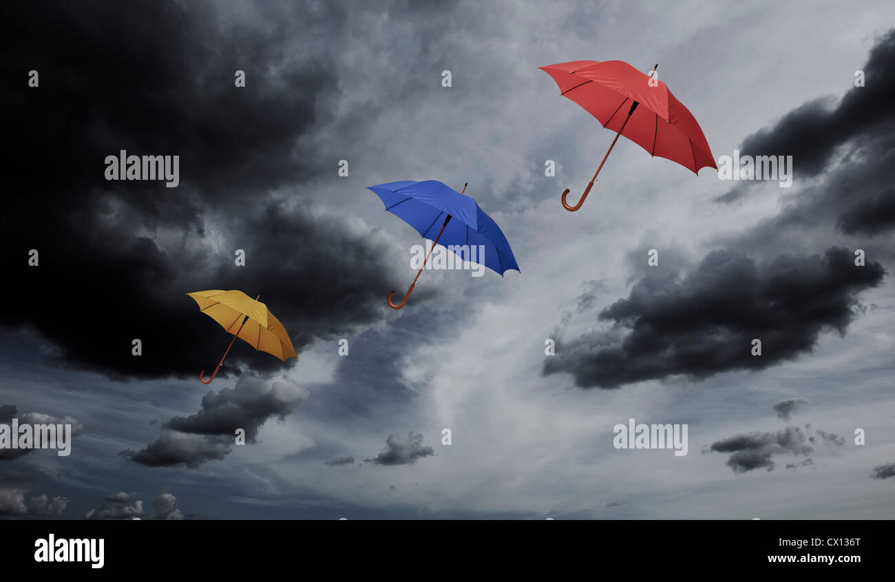 Drei Regenschirme durch bewölktem Himmel schweben Stockfoto