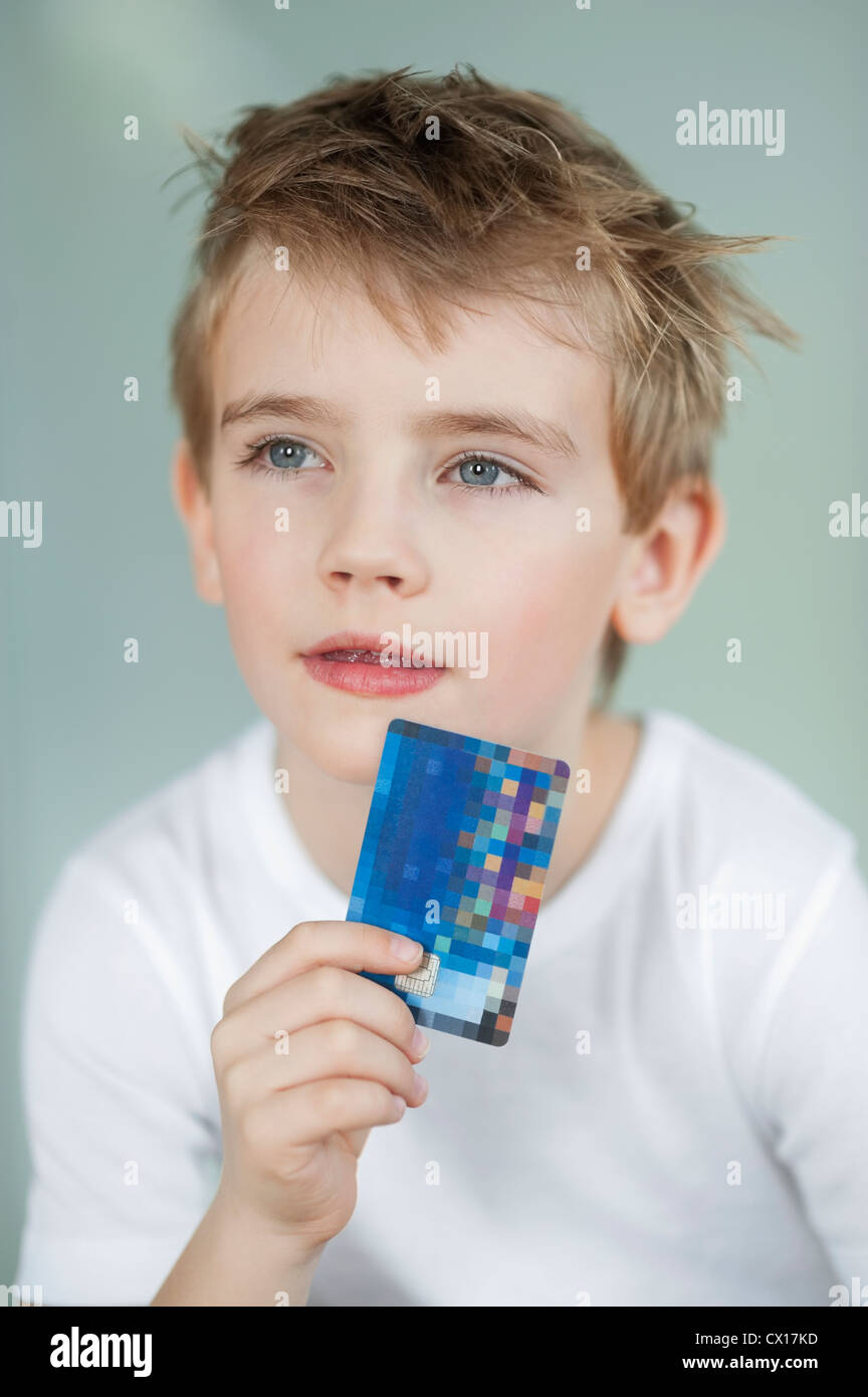 Nahaufnahme eines kleinen Jungen mit Kreditkarte über grauen Hintergrund Stockfoto