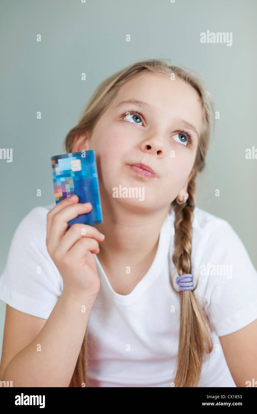 Nachdenkliche junge Mädchen mit Kreditkarte über grauen Hintergrund Stockfoto
