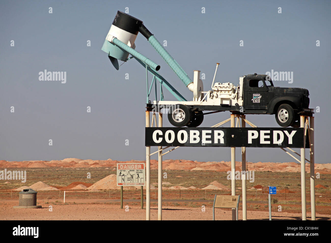 Ortsschild mit typischen Bergbau Fahrzeug in der Landschaft rund um Coober Pedy, Südaustralien, Australien Stockfoto