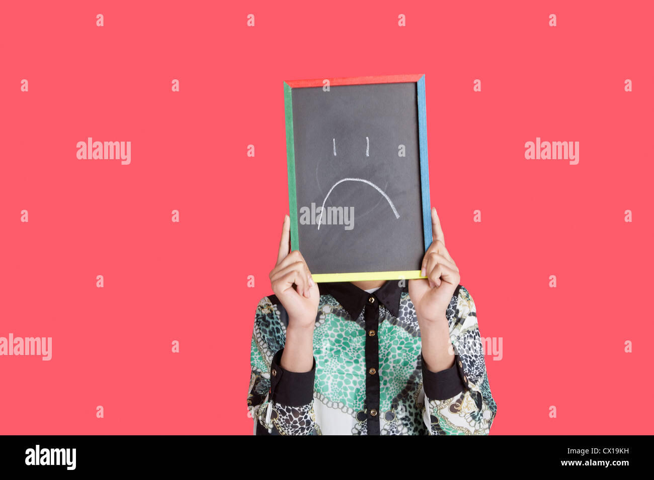 Teenager mit traurigen Smiley Gesicht Schild über rosa Hintergrund Stockfoto