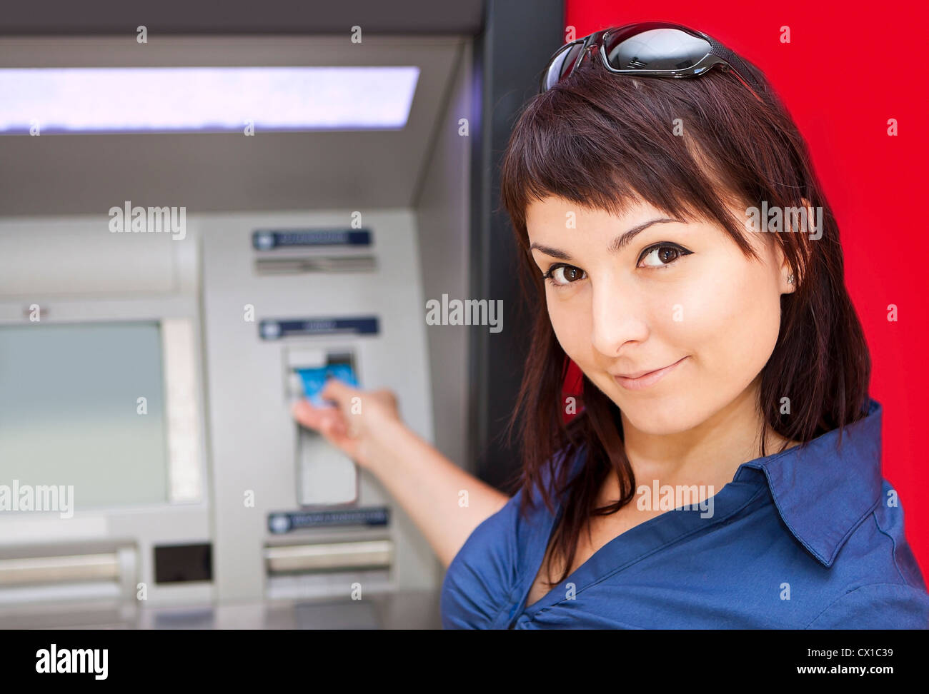 Schöne Frau mit Kreditkarte, sie ist zieht Geld von einem Geldautomaten. Stockfoto