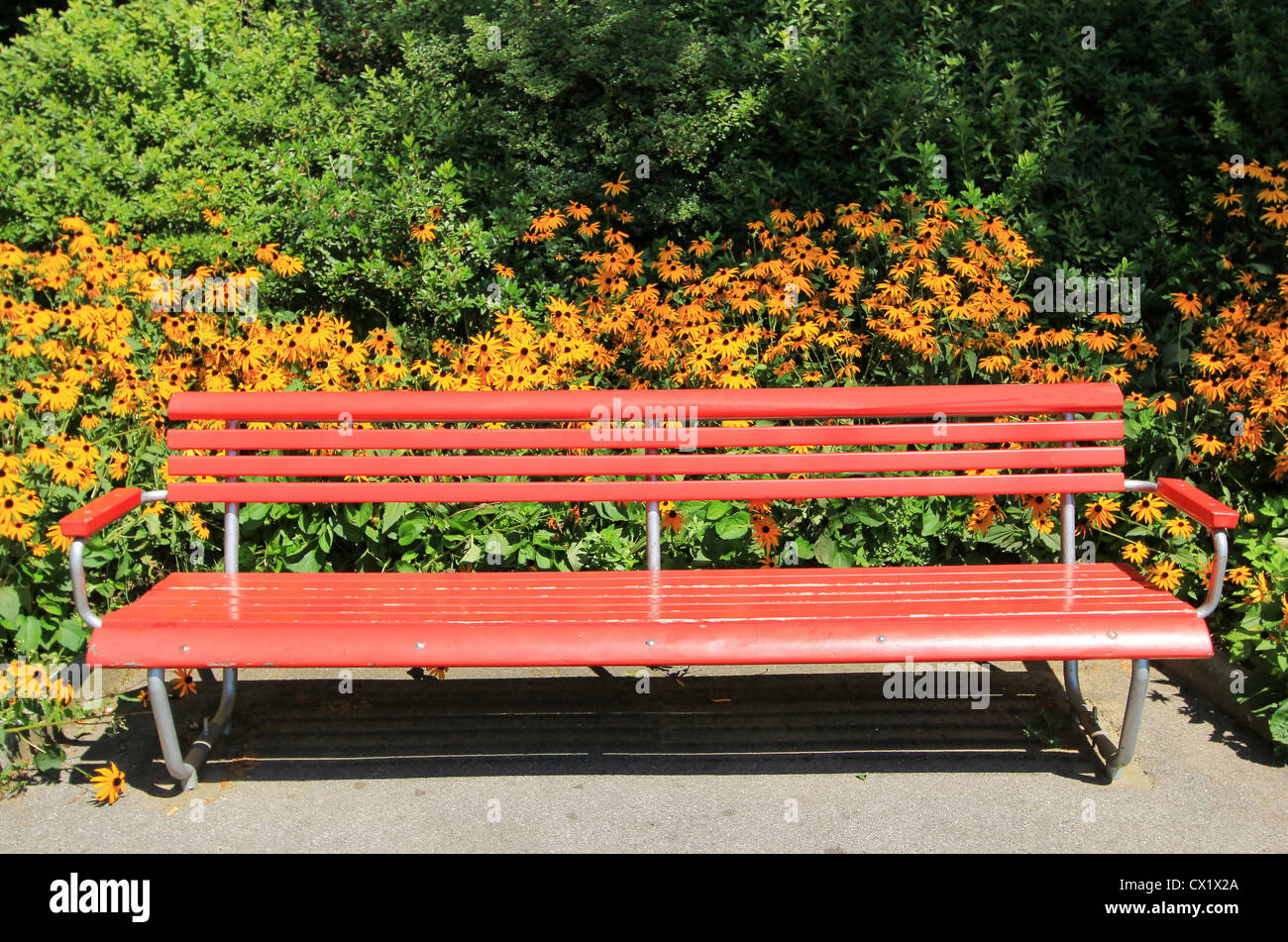 Roten Holzbank in einem Park vor Blumen und Bäume Stockfoto