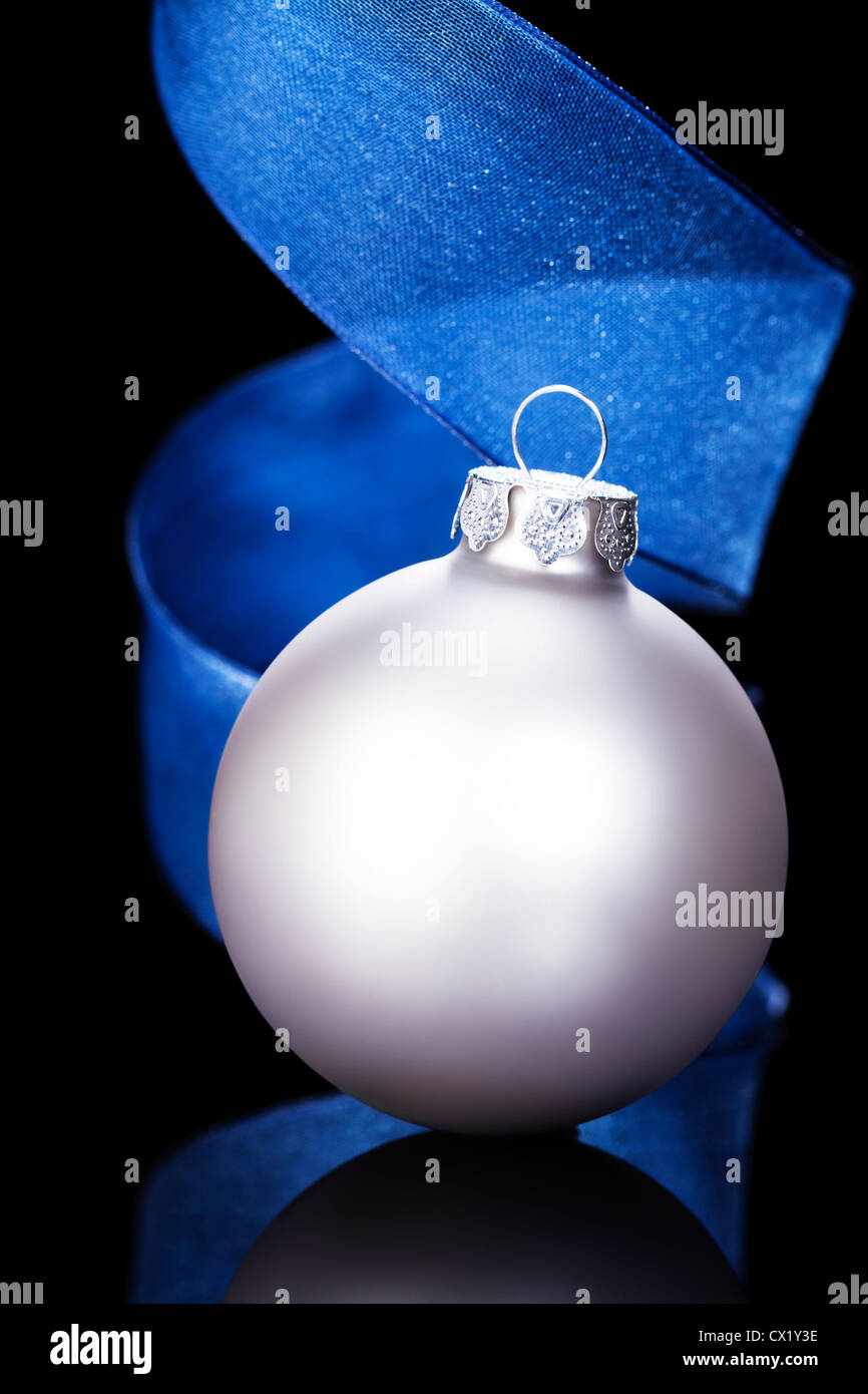 Matt Silber Christmas Ball vor einem blauen Band auf schwarzem Hintergrund Stockfoto