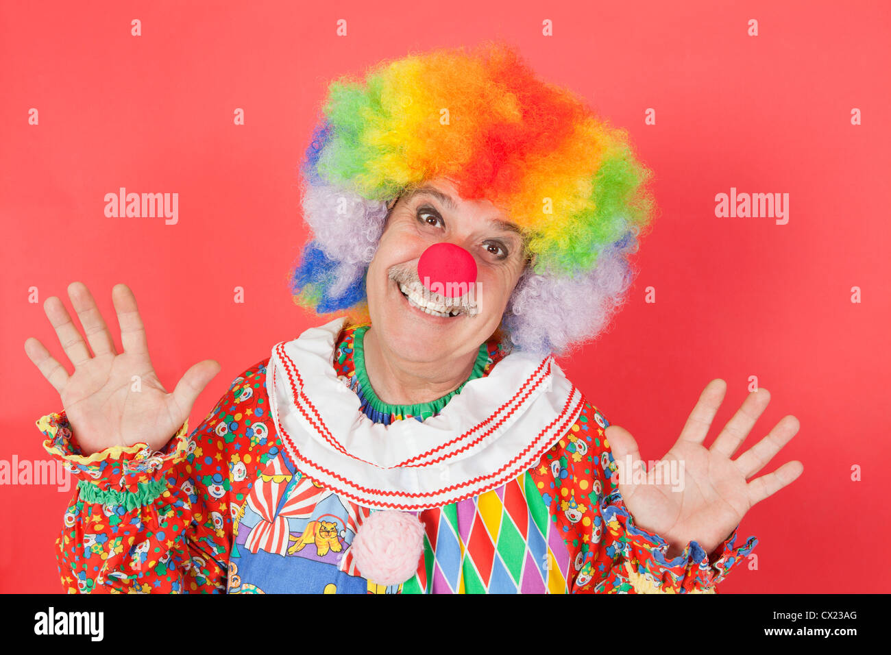 Porträt der lustige Clown mit farbigen Hintergrund erhobenen Armen Stockfoto