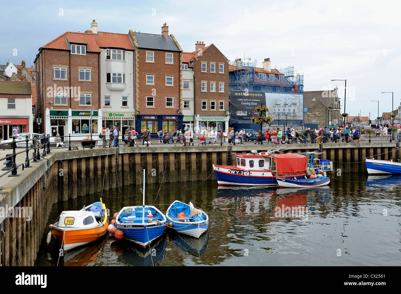 Urlauber im Hafen von Whitby Verdrehungen über die Wand Nord Yorkshire England uk Stockfoto