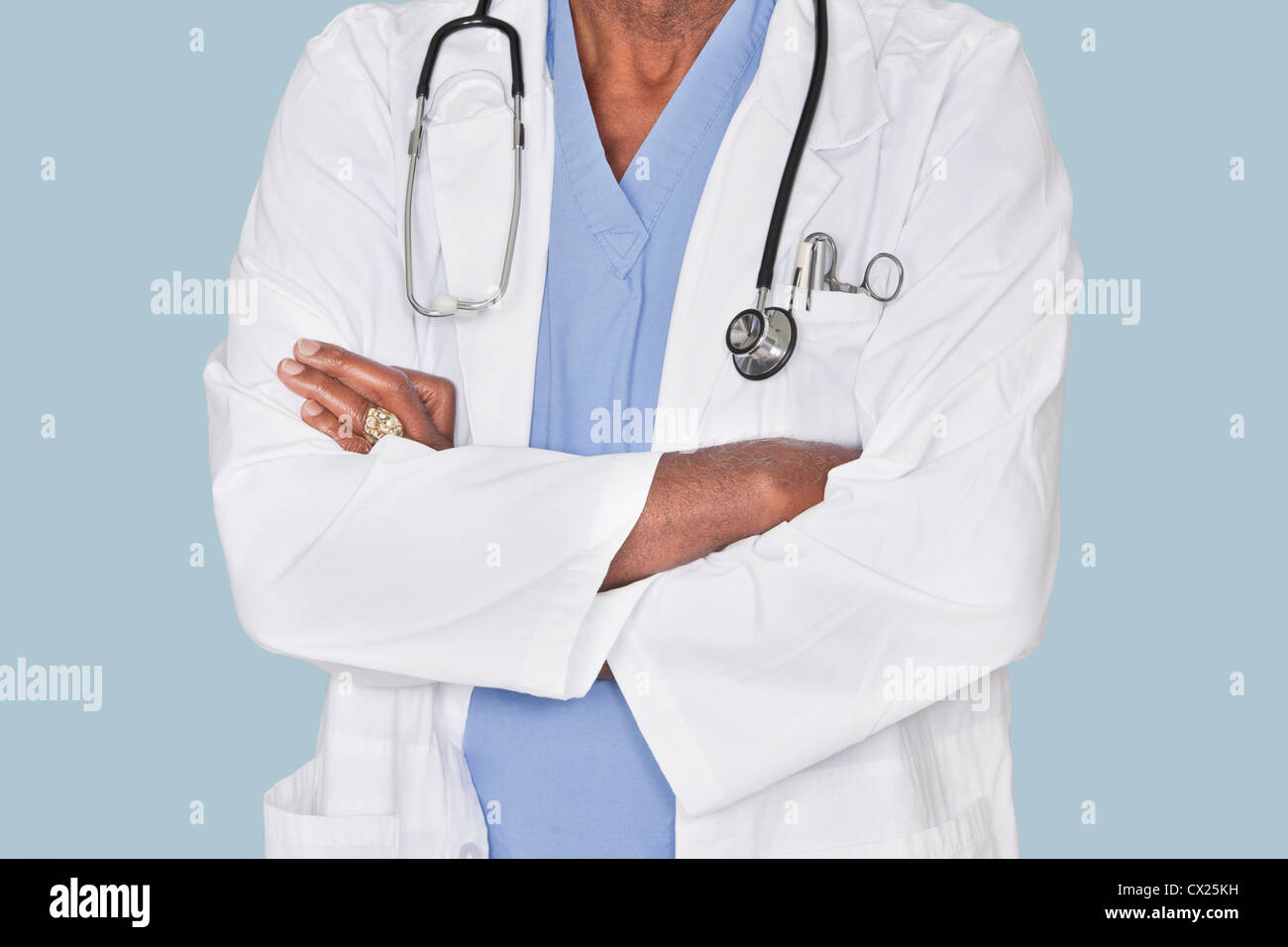 Mittelteil eines Arztes mit verschränkten über hellblauen Hintergrund Stockfoto