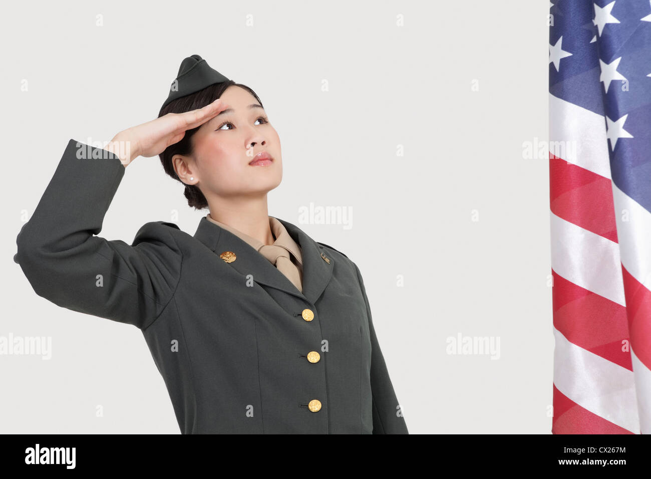 Schweren weiblichen US-Offizier begrüßte amerikanische Flagge über dem grauen Hintergrund Stockfoto