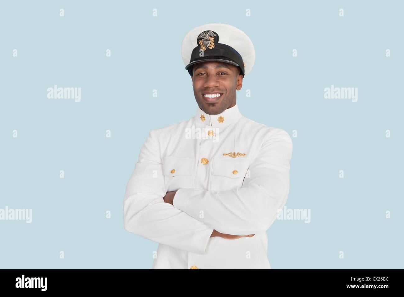 Porträt eines glücklich junge US-Marine-Offiziers mit verschränkten über hellblauen Hintergrund Stockfoto